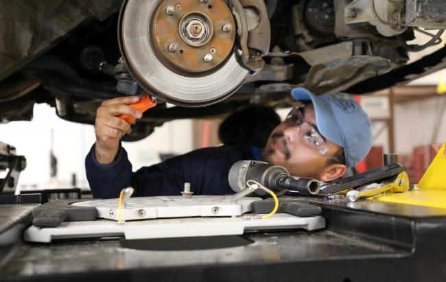 student working on the brake system of a car