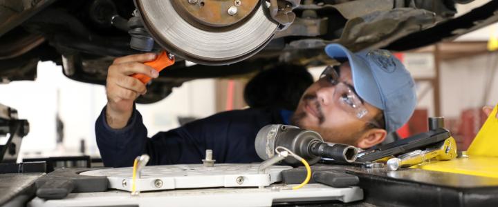 student working on the brake system of a car