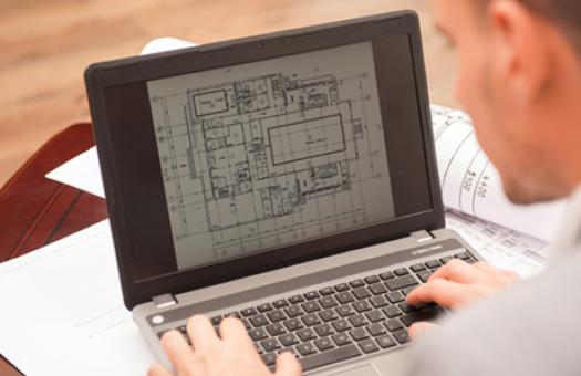 A photo of a generic student looking at an architectural design on a laptop.