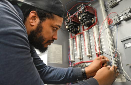 male student working with wires on electrical board 