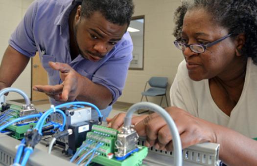male student and female student observe controller in advanced manufacturing class 