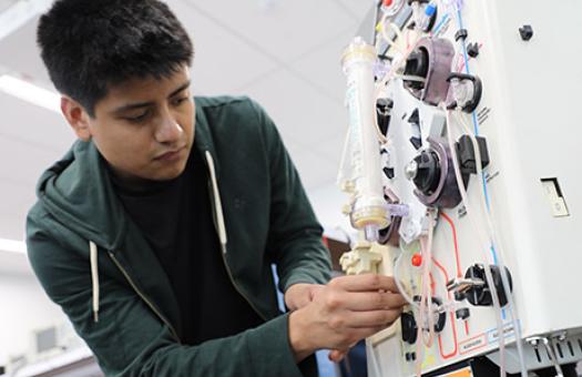biomedical equipment repair student works on sophisticated medical equipment with tubes and dials