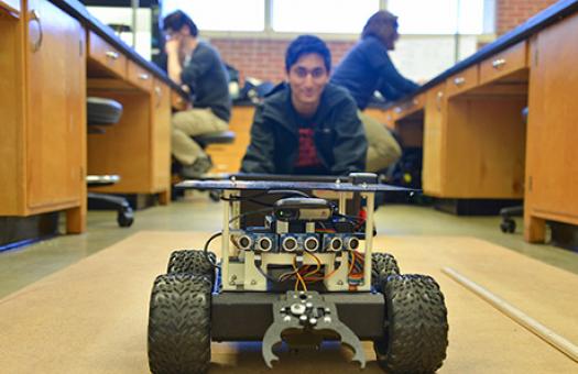 Engineering student waits for a robot vehicle to travel to him