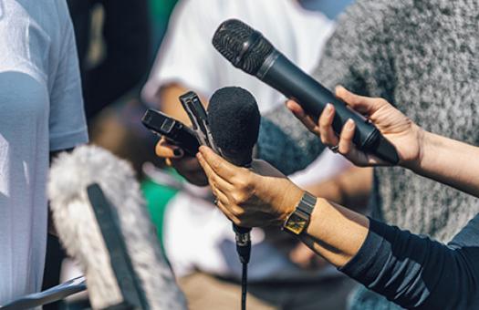 reporters holding microphones out to an unseen speaker