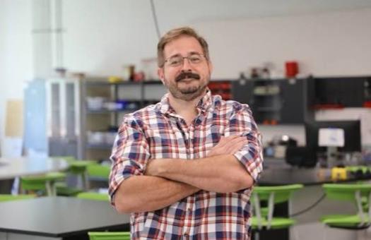 Makerspace Manageer Michael Mattox stands in front of computers and desks in the Newton Makerspace