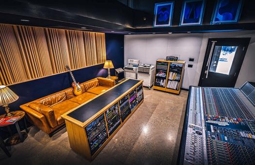 Audio recording room with soundboards, a lounge area, and an electric guitar.