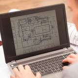 A photo of a generic student looking at an architectural design on a laptop.