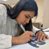Female Architectural Technology student traces drafting outline in class.