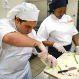 male and students use chef's knife to cut scallions