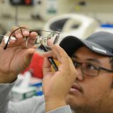 student holding up a pair of glasses and looking at them closely