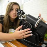 student looking closely into optical equipment to adjust glasses