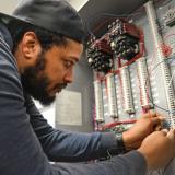 male student working with wires on electrical board 