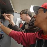 male students using tools on electrical system 