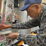 older male student screws wires into electrical board 