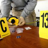 Evidence markers sit on a desk as a Criminal Justice Technology student measures the distance between areas of a training crime scene.
