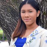 Student smiling in front of tree on main campus. 
