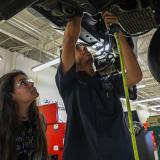 female and male student work on automotive undercarriage