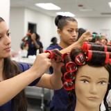Students practice roller sets on dummy heads