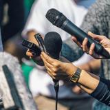 reporters holding microphones out to an unseen speaker