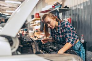 woman working on the engine under the hood of a car