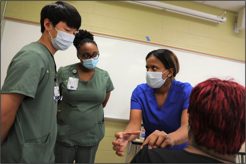 one person showing two other people how to administer a shot